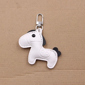 Detailed close-up of a white leather horse keychain with heart stamp and silver lobster clasp