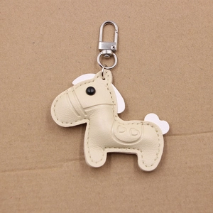 Close-up of beige leather horse charm keychain with fine stitching and silver spring clasp