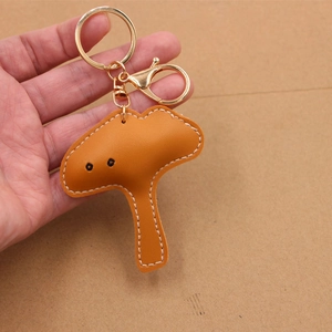 Handheld mushroom leather keychain with gold hardware and detailed white stitching