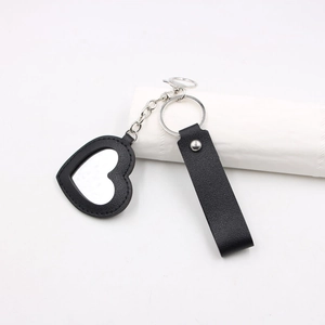 Gros plan d'un porte-clés miroir en forme de cœur avec cadre en cuir noir et chaîne