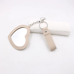 Vue détaillée du porte-clés miroir en cuir beige en forme de cœur avec métal argenté