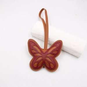 Hollow butterfly leather bag charm in dark reddish-brown and caramel with fine stitching