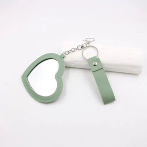Détail du porte-clés miroir de poche en cuir vert en forme de cœur avec coutures