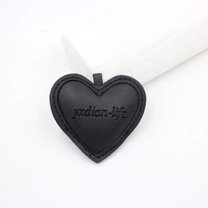 Black heart-shaped leather accessory with stitched edges and embossed textured detail