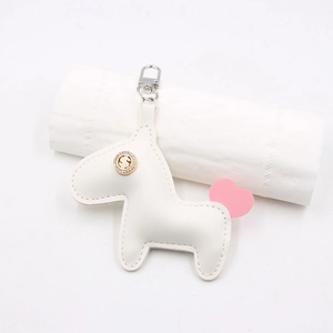 Détail d'un porte-clés cheval en cuir blanc avec signe dollar et petit cœur rose