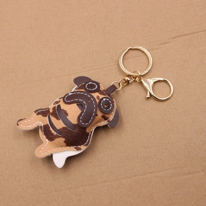 Detailed close-up of a brown leather pug keychain with gold clasp and fine stitching