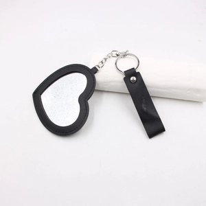 Détail du porte-clés miroir en forme de cœur avec cadre en cuir noir et anneau métal