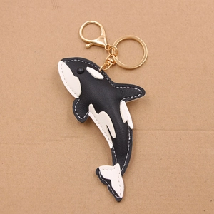Detail of handcrafted black and white leather orca keychain with gold metal lobster clasp