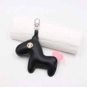 Détail du porte-clés poney en cuir noir avec signe dollar et breloque coeur rose