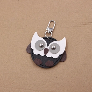 Close-up of a handmade owl leather keychain with silver rivets and metal spring clasp