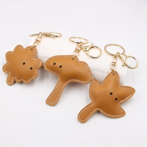 Detailed view of leather leaf keychains with gold hardware and white stitching