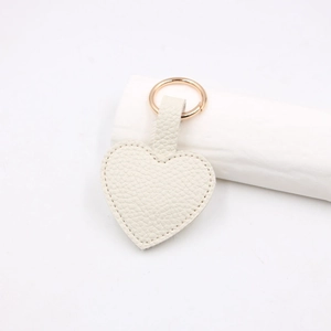 Detail view of heart-shaped cream litchi leather keychain with golden metal ring