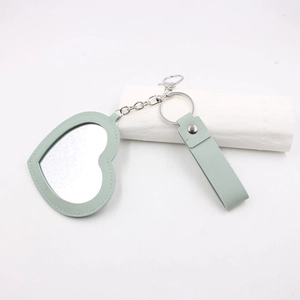Détail du porte-clés miroir en cuir vert menthe en forme de cœur avec chaîne en métal
