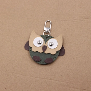 Close-up of green leather owl keychain with textured lychee grain and silver snap hook