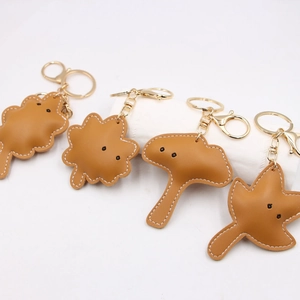 Detailed view of leather leaf keychains with white stitching and gold metal hardware