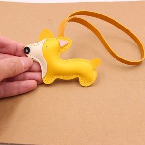 Dettaglio delle cuciture bianche e del cuoio giallo del ciondolo per borsa a Corgi