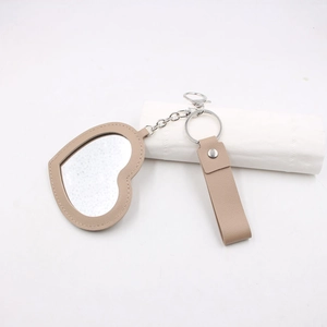Détail du porte-clés miroir en cuir beige en forme de cœur avec anneau en métal argenté