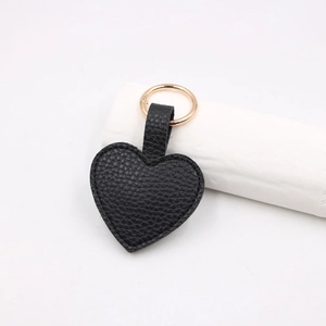 Close-up of black heart-shaped leather keychain with lychee texture and golden metal ring