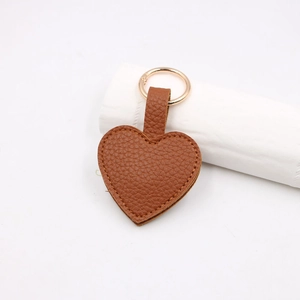 Macro shot of brown lychee texture PU leather heart keychain with golden metal spring ring