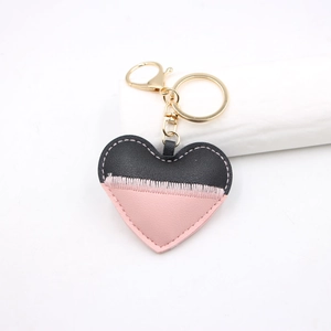 Detail of pink and black heart leather keychain with white hand-stitched seams and gold clip