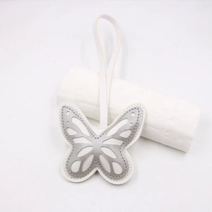 Macro view of silver hollow butterfly charm with layered faux leather and white stitching