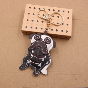 Handmade black and white leather pug keychain with golden metal clasp on paper background