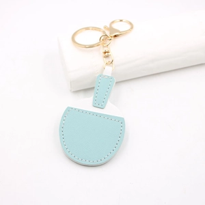 Detail view of light blue leather table tennis racket keychain with gold metal hardware