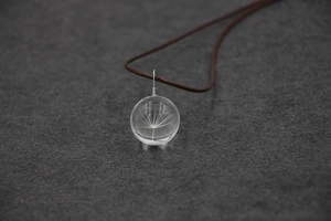 Vue détaillée d'un pendentif en sphère de verre avec une graine de pissenlit réelle