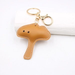 Detail of mushroom leather keychain with brown caramel finish and golden metal ring