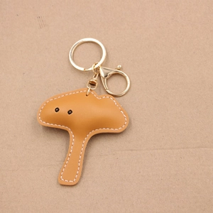 Detail of mushroom leather keychain with white contrast stitching and golden clasp hardware