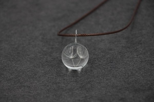 Vue macro détaillée d'un pendentif en boule de verre avec de vraies graines de pissenlit