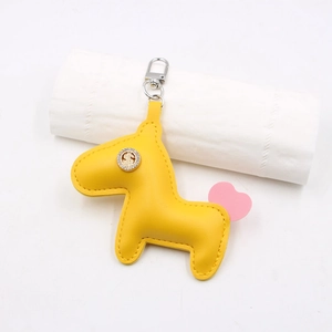 Détail du porte-clés cheval en cuir jaune avec badge dollar et pendentif cœur rose