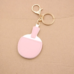Detailed close-up of pink leather table tennis racket keychain with gold metal clasp