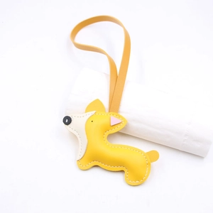 Dettaglio di ciondolo per borsa a forma di Corgi in pelle con cuciture e cordino giallo