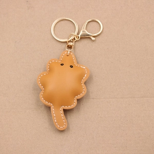 Detailed close-up of brown leather leaf-shaped keychain with decorative hand-stitched edges