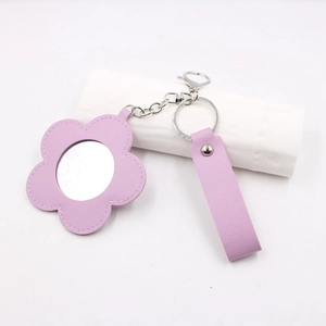Détail du porte-clés miroir fleur en similicuir violet avec fermoir métallique argenté