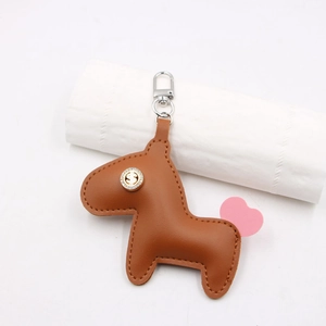 Détail macro du porte-clés cheval en cuir marron avec queue en cœur rose et clip