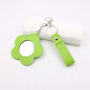 Détail d'un porte-clés fleur en cuir vert avec mini miroir et fermoir argenté