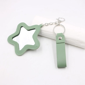 Détail d'un porte-clés miroir en cuir vert sauge en forme d'étoile avec anneau métal
