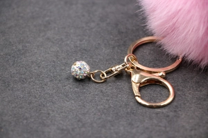 Close-up of pink fluffy faux fur pompom keychain with a sparkling rhinestone ball pendant