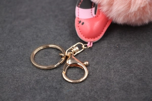 Détail d'un porte-clés pompon en fausse fourrure rose avec mini chaussure et fermoir doré