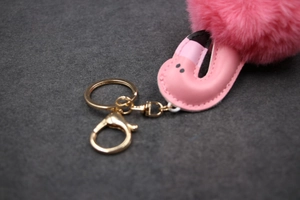 Détail macro du porte-clés flamant rose en peluche avec anneau en métal doré