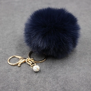 Detail of navy blue faux fur pompom keychain with golden clasp and sparkling crystal ball
