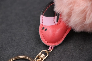Détail d'un porte-clés pompon rose avec empiècement en cuir cousu et mousqueton doré chic