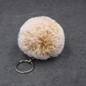 Detailed macro view of fluffy light coffee faux rabbit fur keychain with silver metal ring