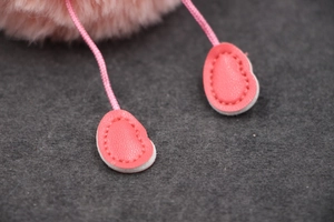 Gros plan détaillé des breloques en cuir rose en forme de cœur avec coutures fines