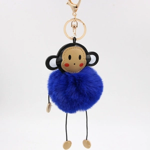 Detailed view of monkey plush keychain with blue fur ball and gold metal clasp hardware