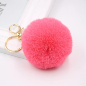 Close-up of fluffy magenta faux fur ball keychain with golden metal ring and lobster clasp