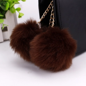 Detail of soft brown faux fur pompom keychain with elegant gold chain on a black bag