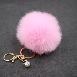 Detail of pink faux fur pompom keychain with gold plating and sparkling rhinestone ball